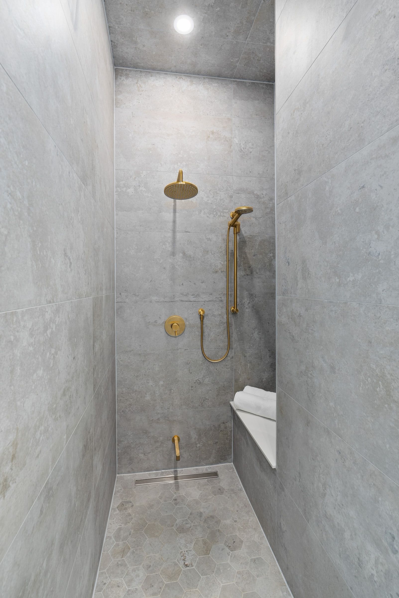 Marble ensuite shower with brass fittings and a glass enclosure.